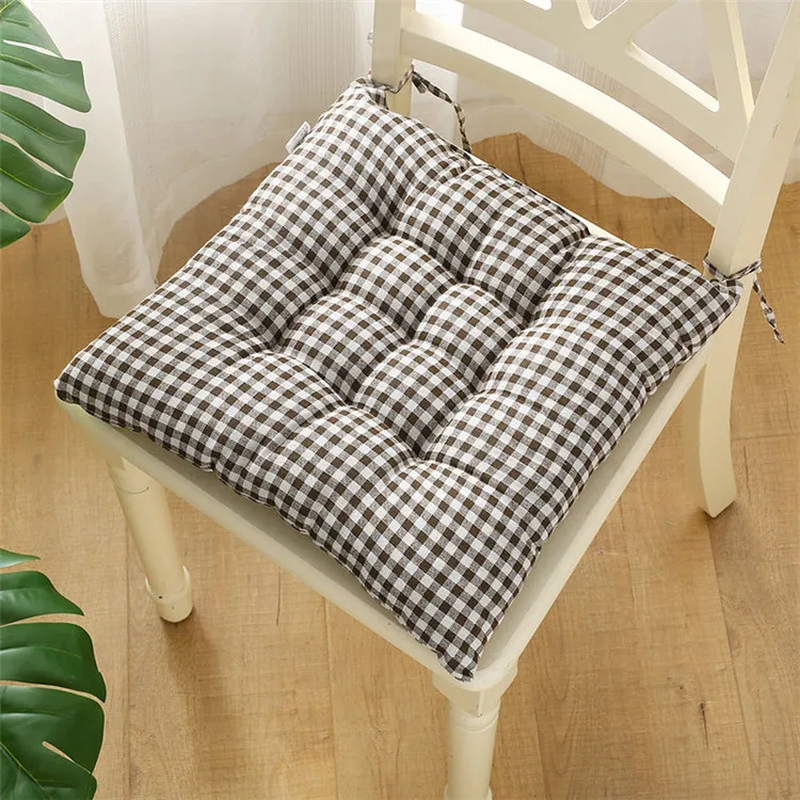 Checkered chair cushion on a wooden chair with a plant in the background صورة ثانوية