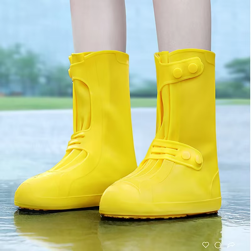 Yellow rain boots worn by a person standing in water with a blurred natural background صورة ثانوية